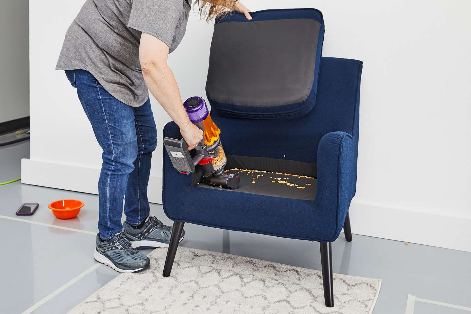 A person using the Dyson V12 Detect Slim to clean up food inside an armchair