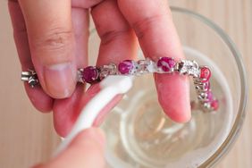 Jeweller hand cleaning and polishing vintage jewelry red ruby and silver braclet