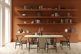 Dining room with red painted wall and open shelving, oval dining table