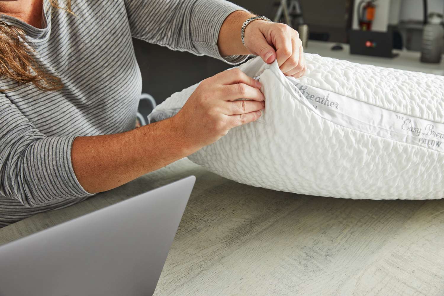 Person zipping up the Nest Bedding Easy Breather Natural Pillow displayed on table