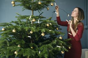 How to Hang Christmas Lights, woman hanging lights on tree