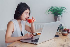 person drinking juice while planning a PowerPoint party on a laptop