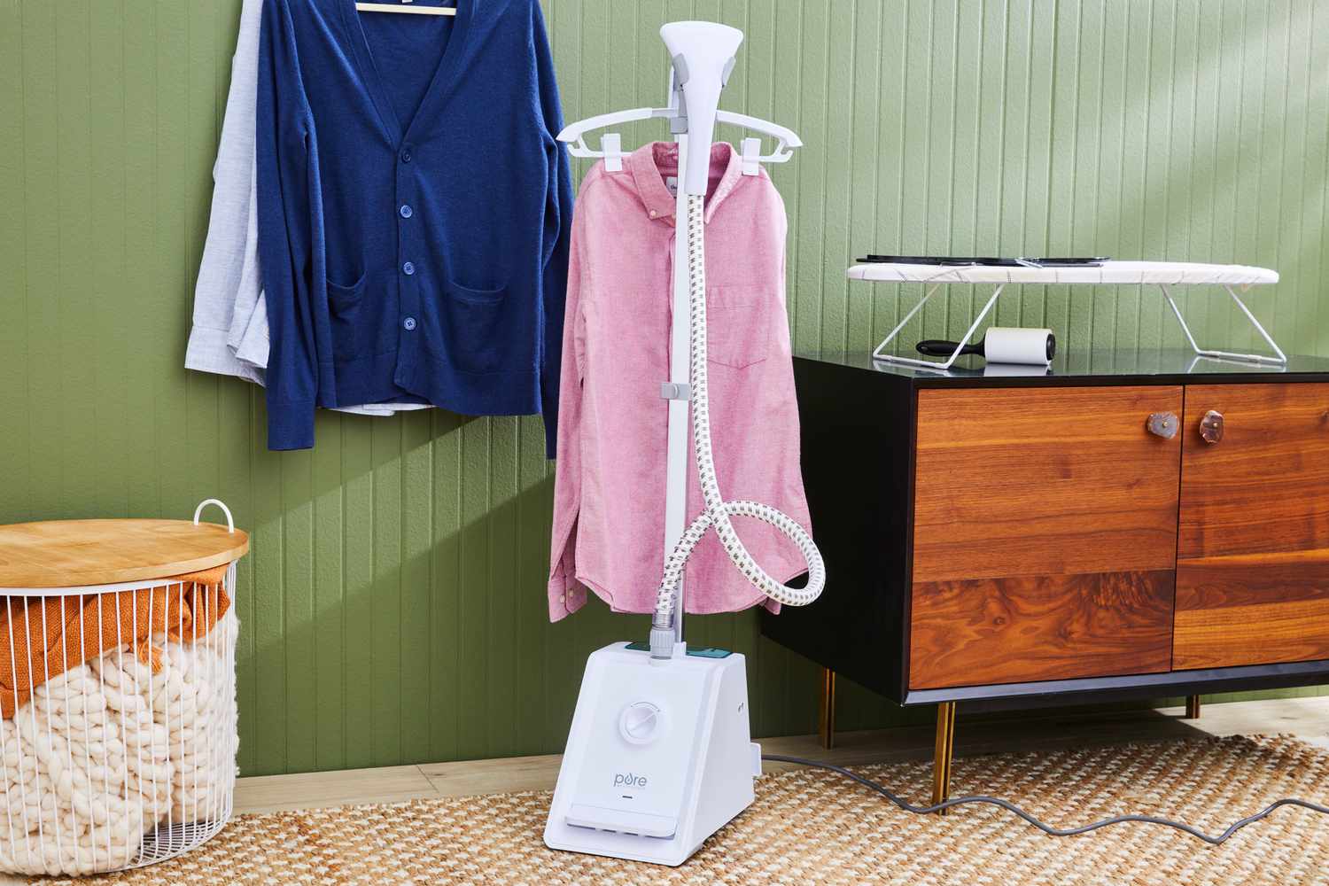 The Pure Enrichment PureSteam Pro Upright Clothes Steamer sitting in a room with a shirt hanging off it's rack.