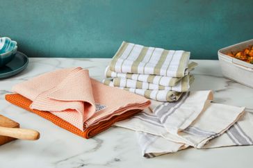 A variety of kitchen towels on a white marble countertop