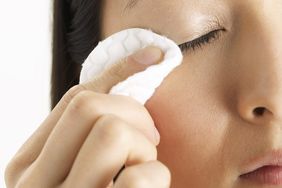 Person removing mascara and wiping eye with cotton pad