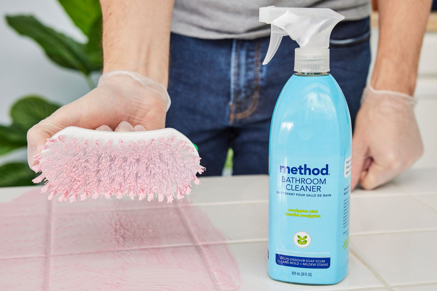 A person scrubs a countertop using Method Bathroom Cleaner Tub + Tile Eucalyptus Mint Spray