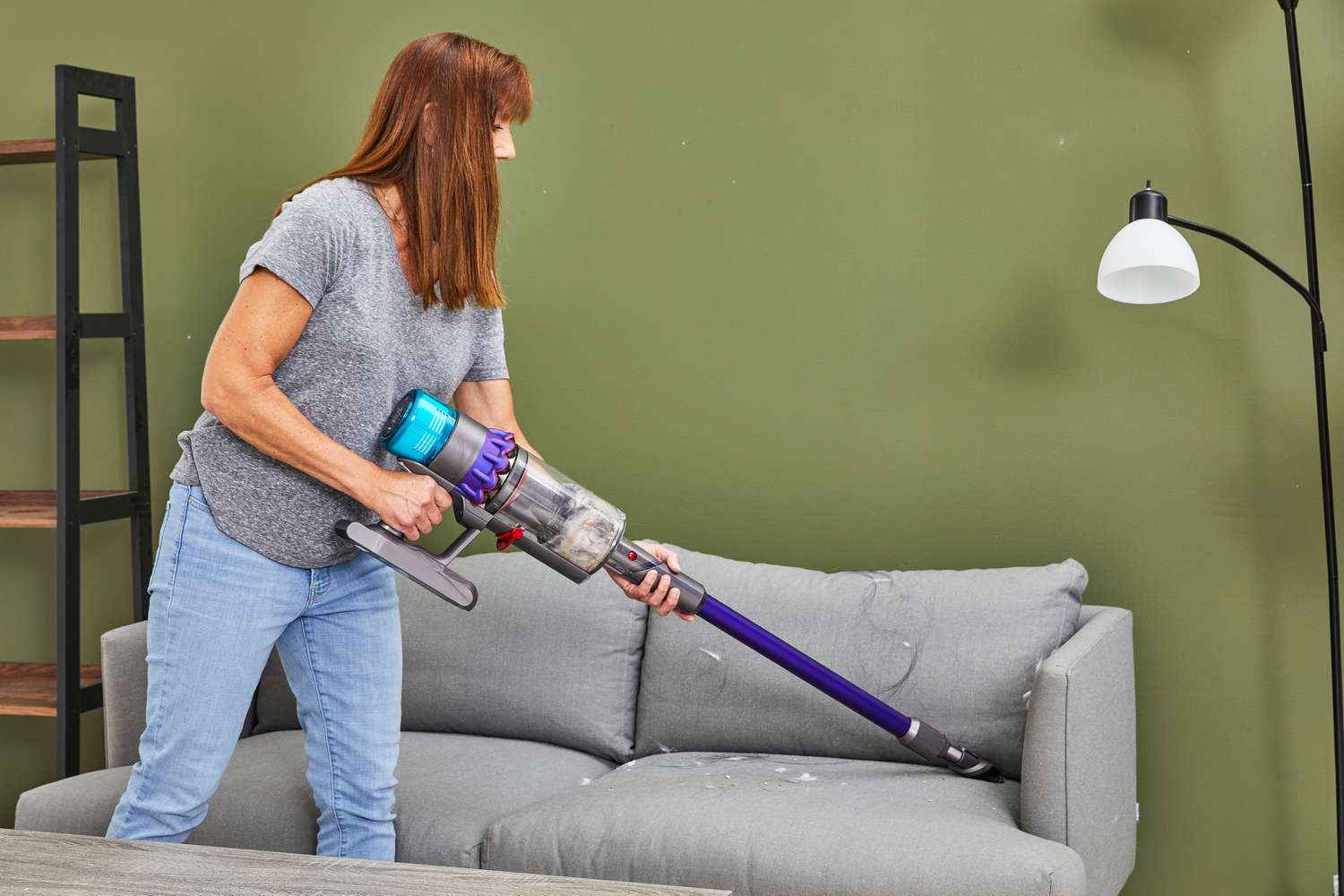 A person using the Dyson Gen5detect to vacuum a sofa in a living room