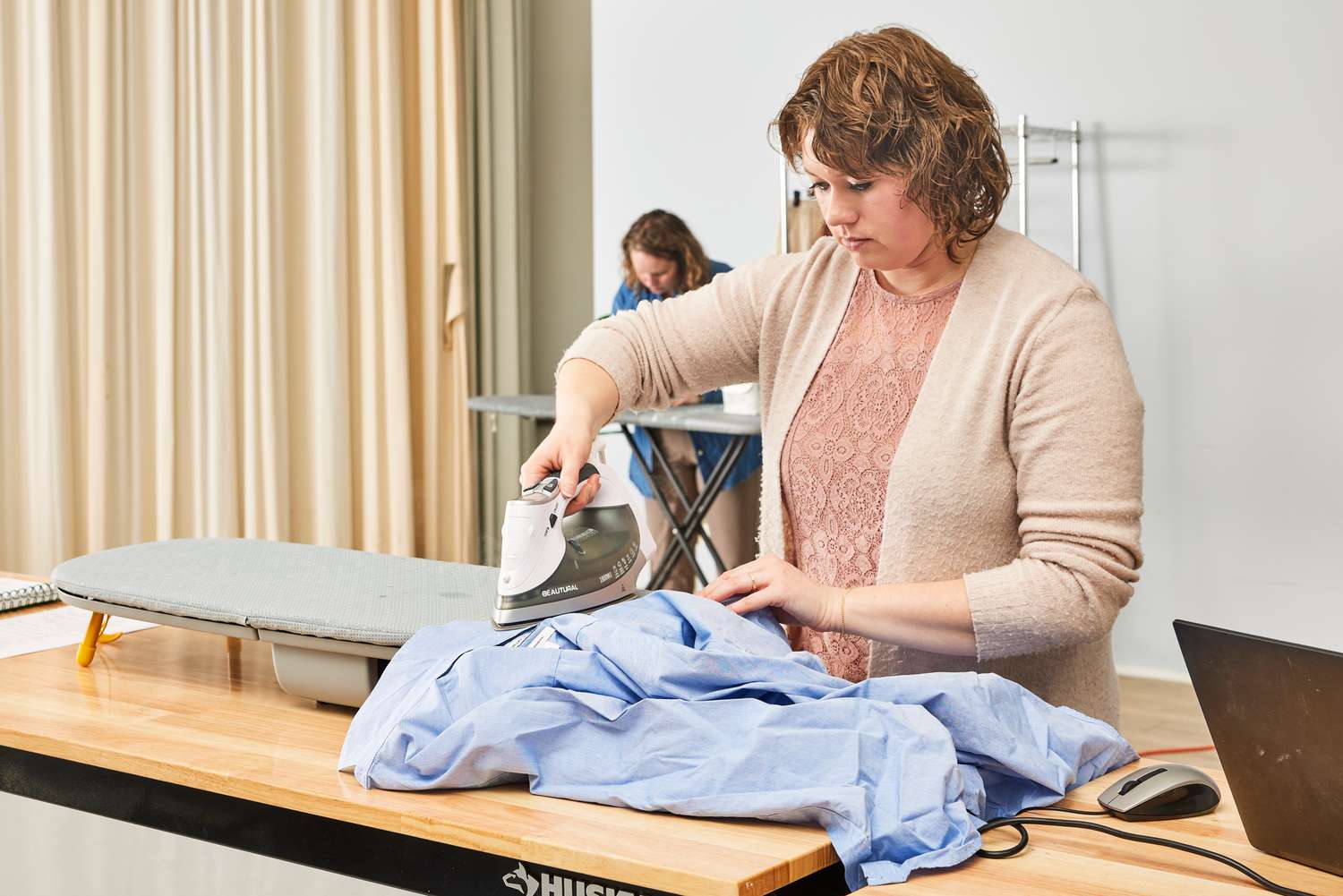 A person ironing a shirt on the Joseph Joseph Pocket Folding Ironing Board