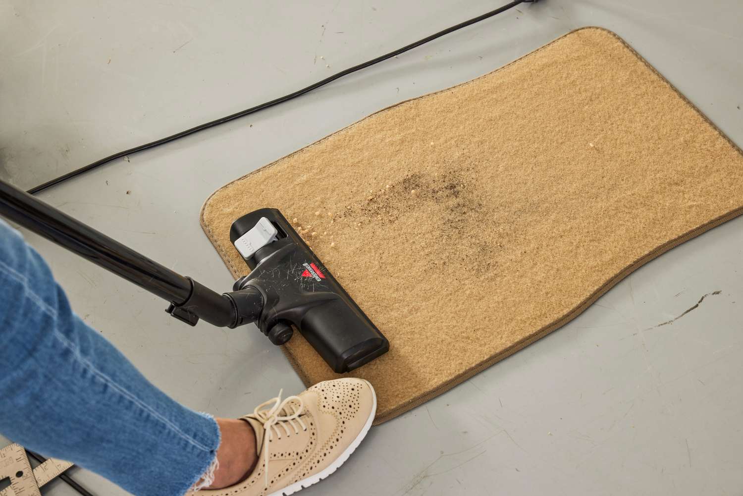 A person vacuums a car mat with the Bissell Zing Bagless Canister Vacuum, 2156A
