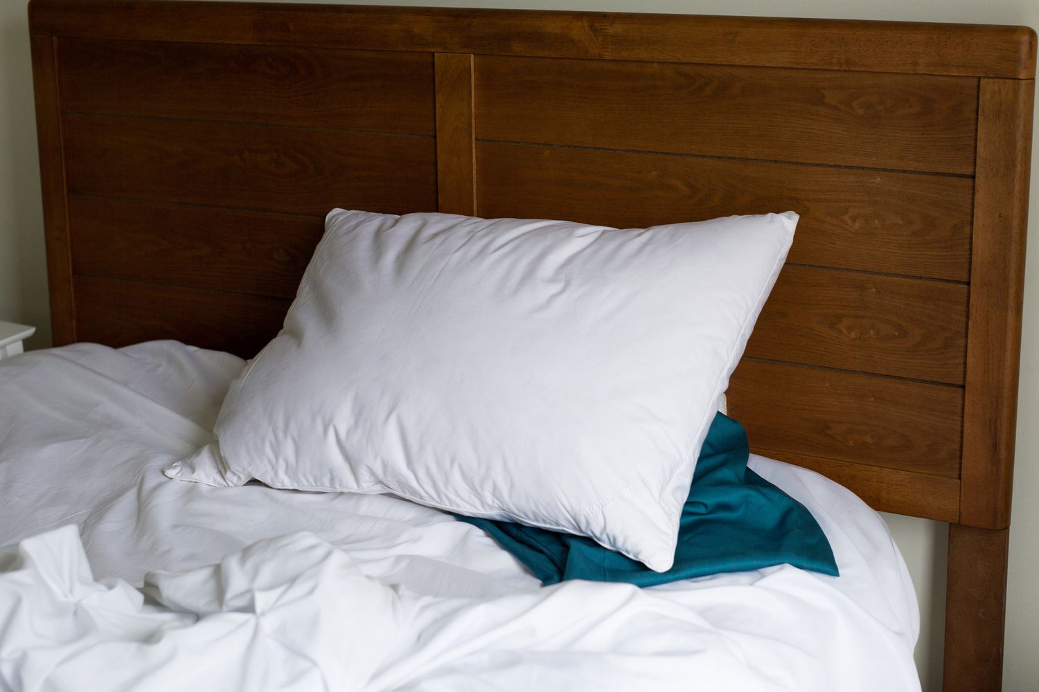 Boll & Branch Down Chamber Pillow sitting on blue pillowcase on top of a bed