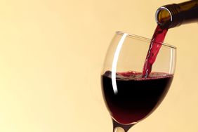 Red wine being poured into a wine glass on a yellow background