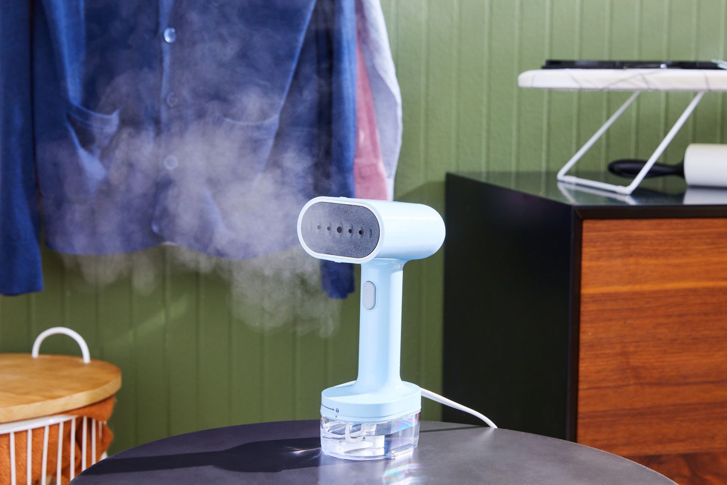 The Proctor Silex Compact 2-in-1 Garment Steamer/Iron on a table with steam coming out of it.