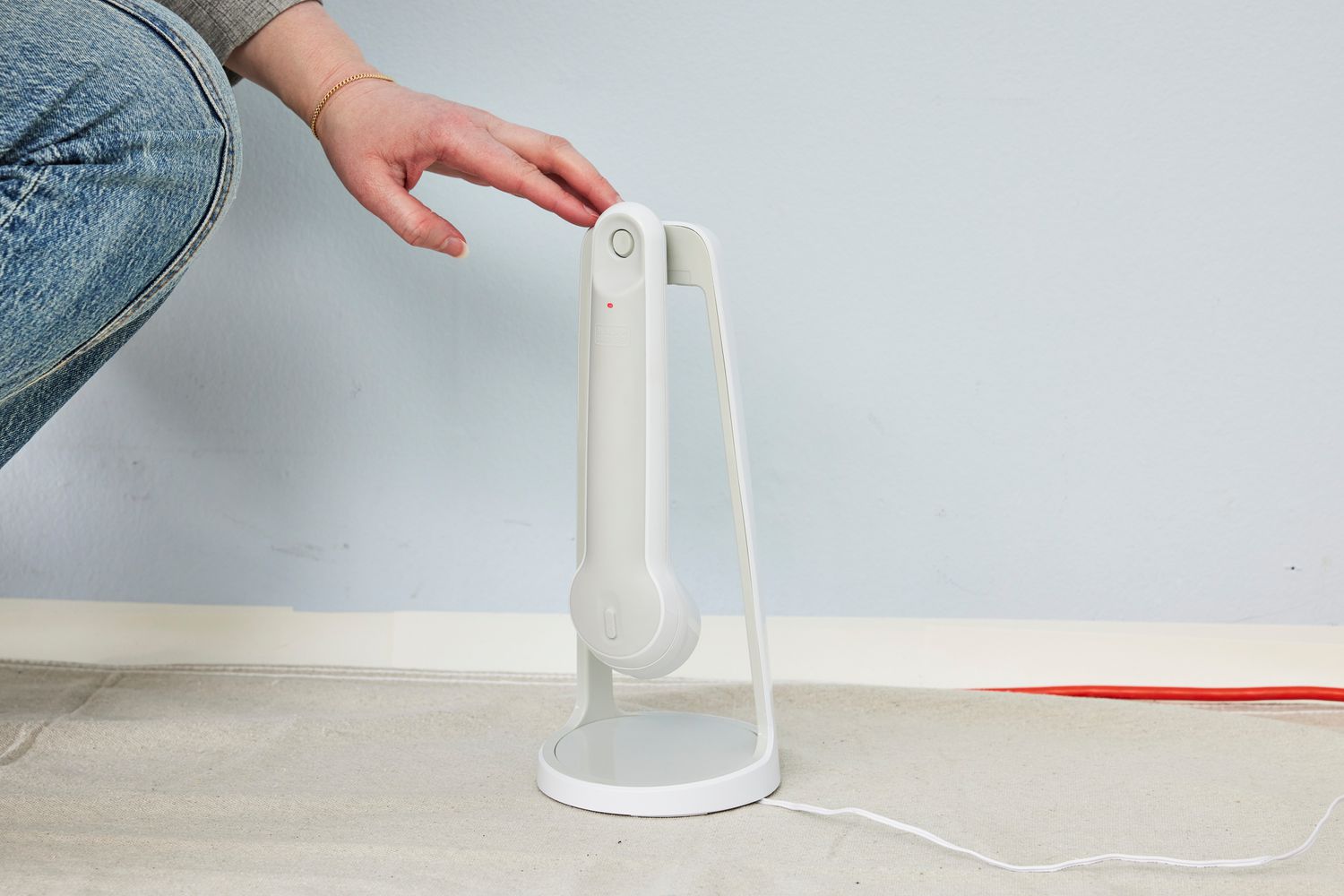 Hand touches a Black+Decker Grimebuster Pro Power Scrubber Brush on its stand