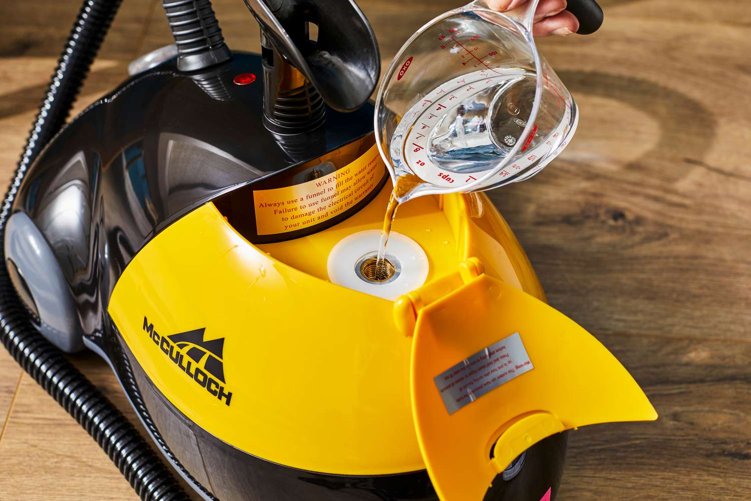 A person fills the top of the McCulloch MC1275 Heavy Duty Steam Cleaner canister with water