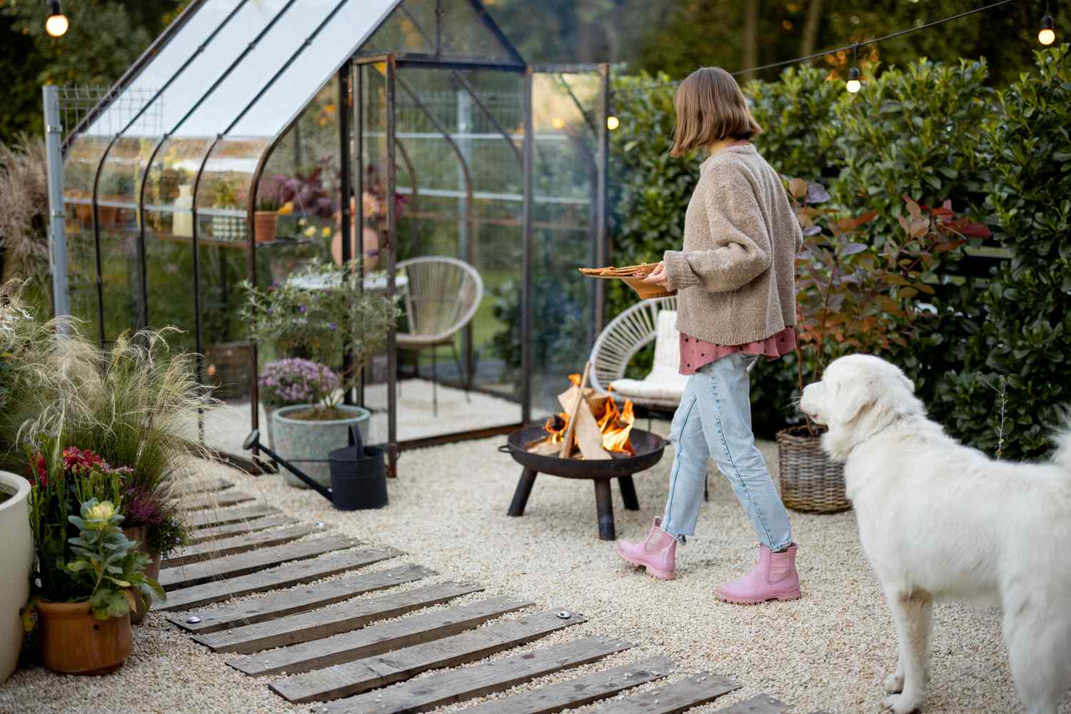 woman and dog in backyard next to fire and greenhouse