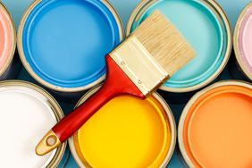 Two Rows of Paint Cans With a Clean Paint Brush Sitting on Top