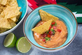 Turquoise bowl with queso or mexican cheese dip and corn chips,