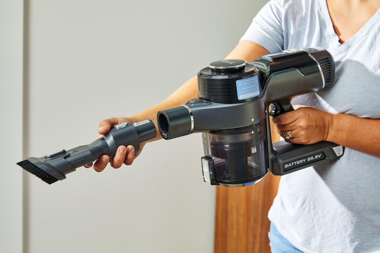 A person puts the brush attachment into the top of the Levoit VortexIQ 40 Cordless Stick Vacuum.