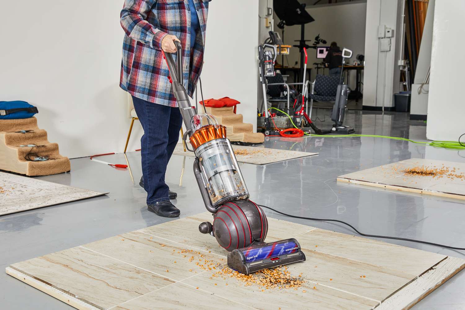 A person using a Dyson Ball Animal 3 Extra to clean a pile of crumbs from a granite floor