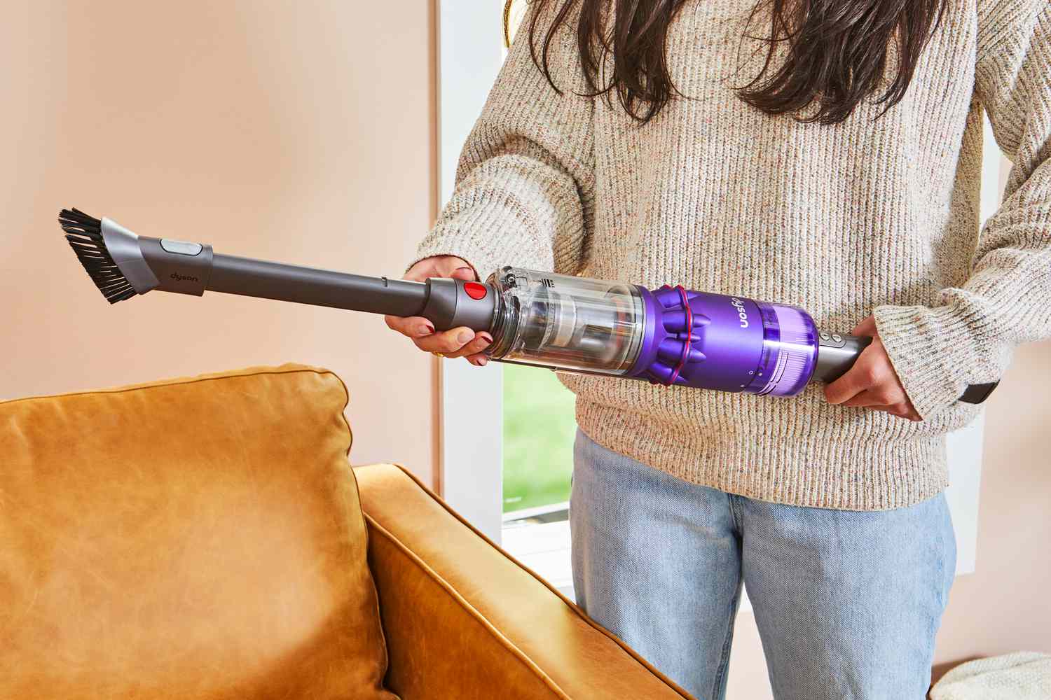 Person attaching a nozzle to the Dyson Omni-Glide+ Cordless Vacuum next to a couch