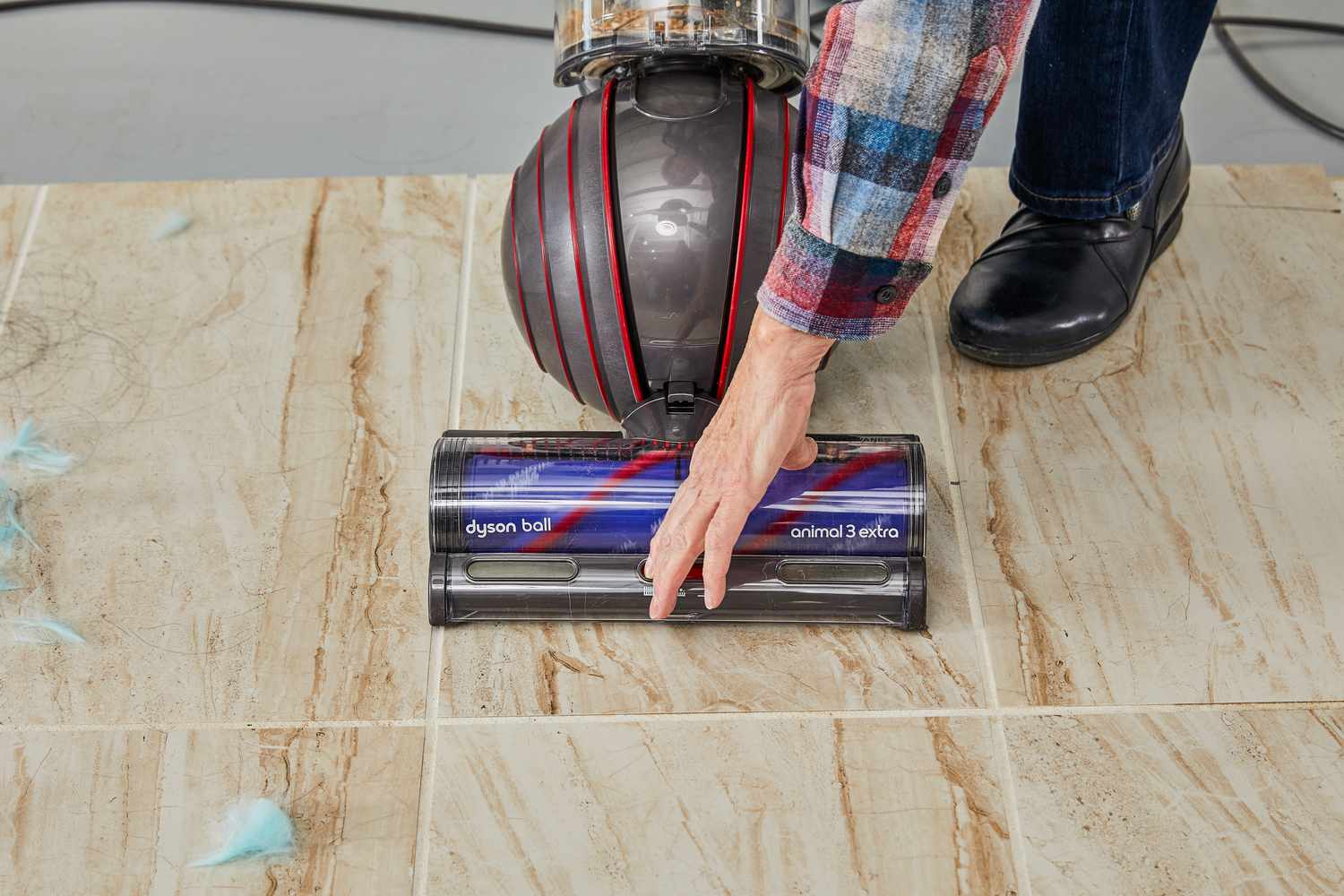 A hand adjusting the Dyson Ball Animal 3 Extra bottom to the granite floor