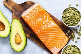 A spread of foods high in magnesium, including avocado, salmon, and pumpkin seeds