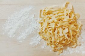 High Angle View Of Pasta And Flour On Wooden Table