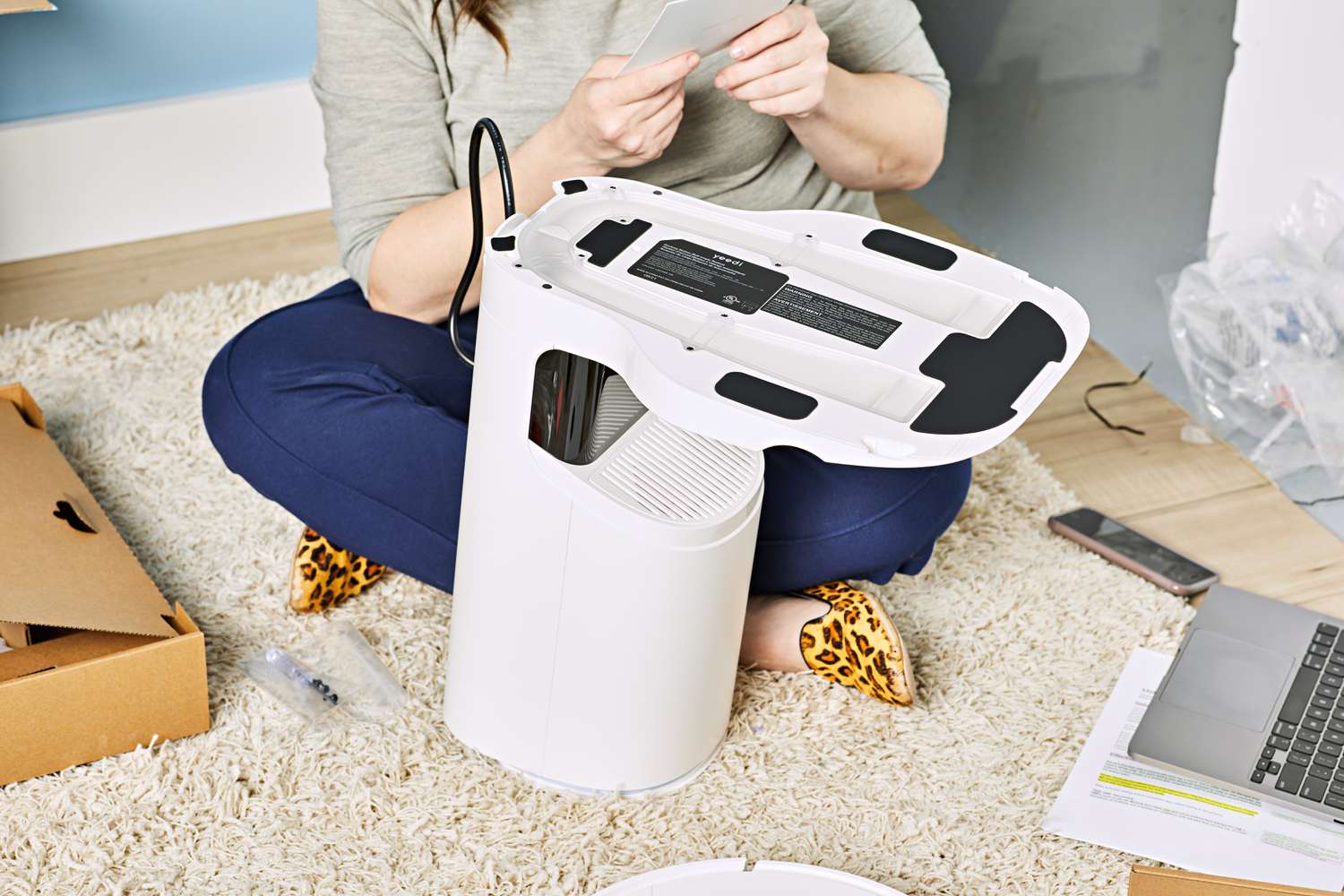 Person assembling the Yeedi Vac Station 3000Pa while sitting on a rug 