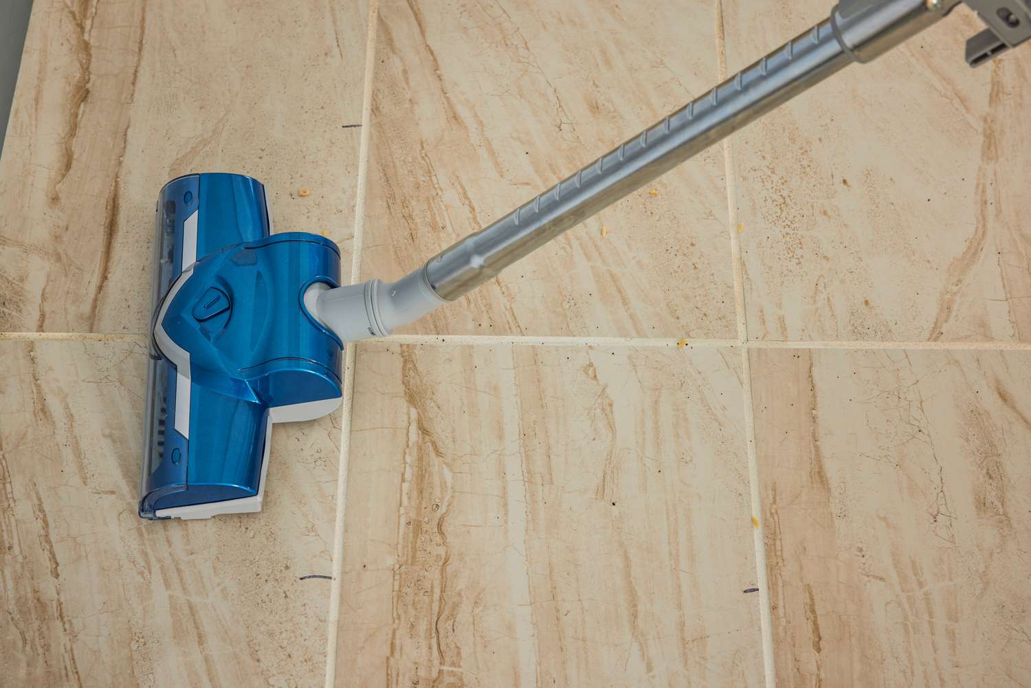 A close-up of the Kenmore Compact Bagless Canister Vacuum's brush head being used on tile floors.