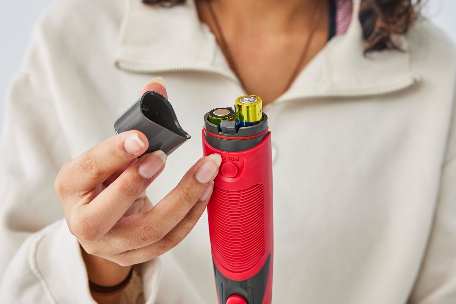 Person holding closure for the battery compartment on the Rubbermaid Reveal Power Scrubber