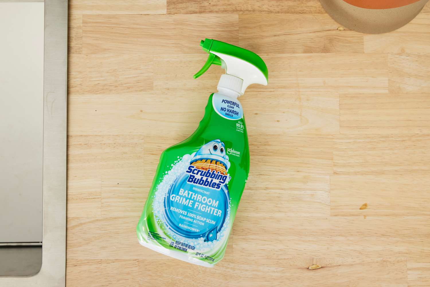 A bottle of Scrubbing Bubbles Disinfectant Bathroom Grime Fighter Spray on a wooden countertop