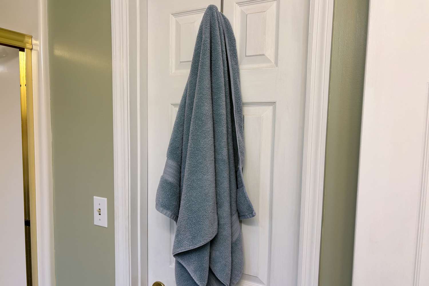 The Better Homes & Gardens Signature Soft Bath Towel hangs on a door hook
