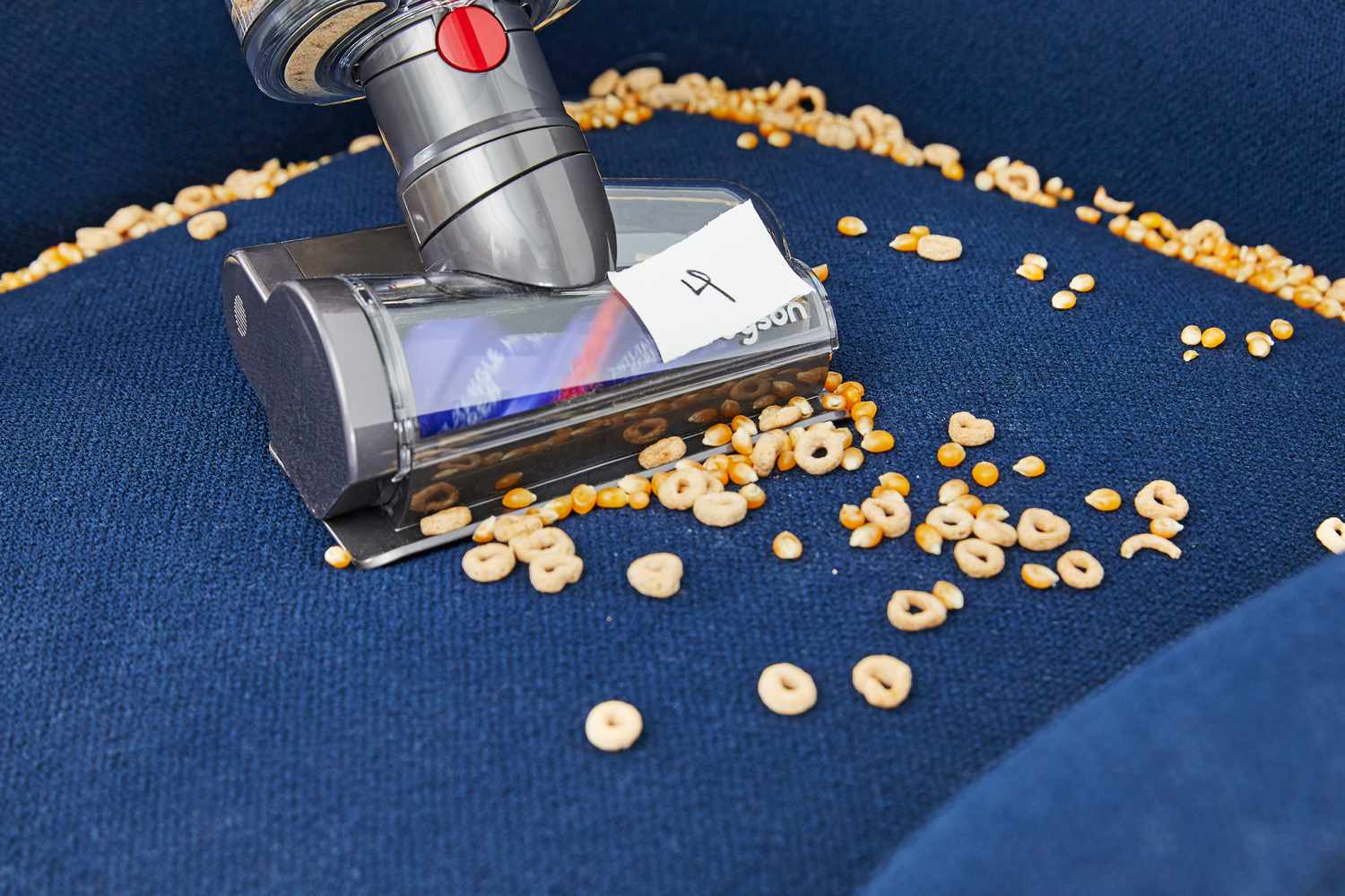 Dyson V12 Detect Slim cleaning cheerios and popcorn kettles off the cushion of an armchair