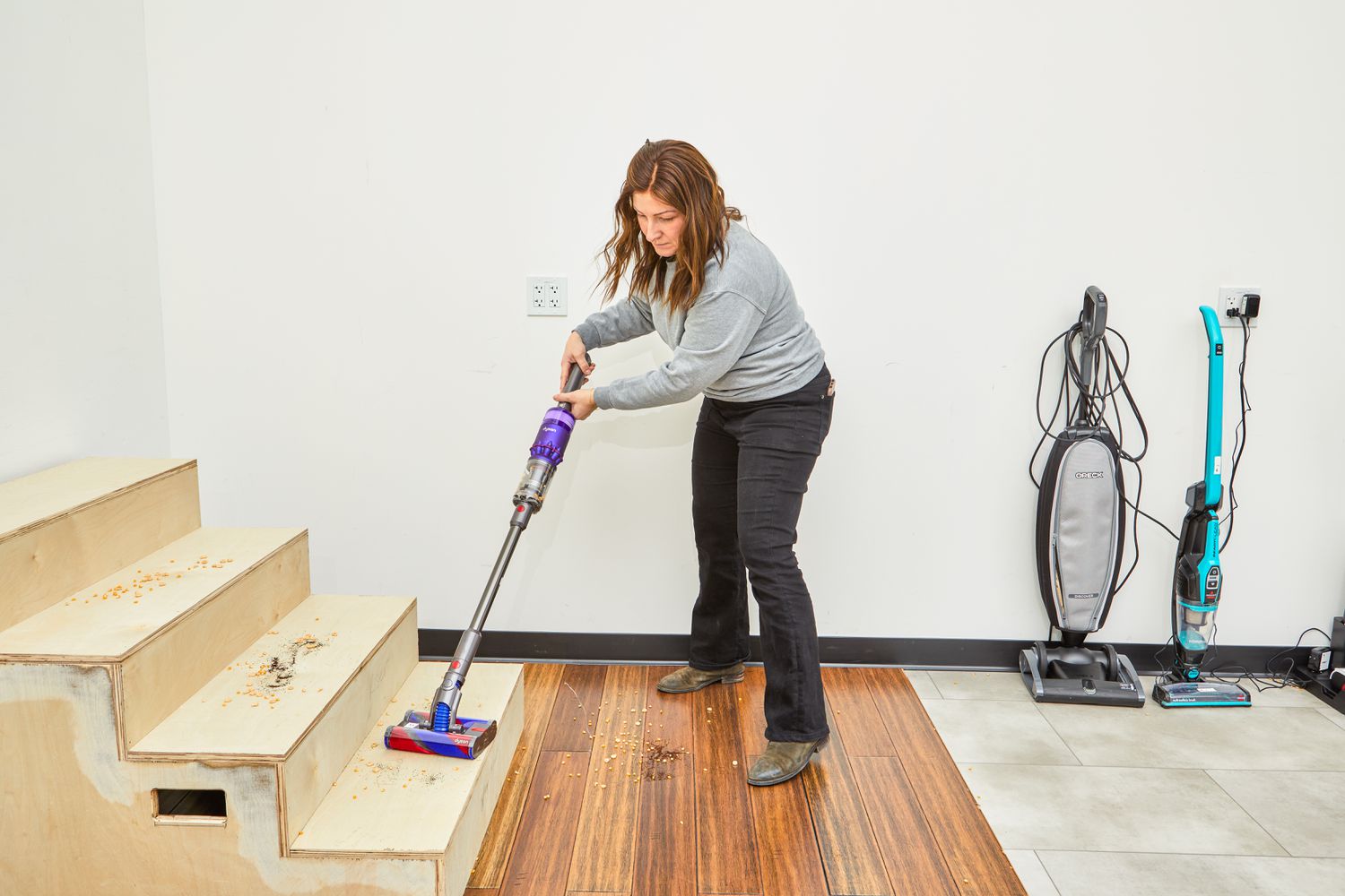 Person using a Dyson Omni-Glide+ Cordless Vacuum to clean wood stairs