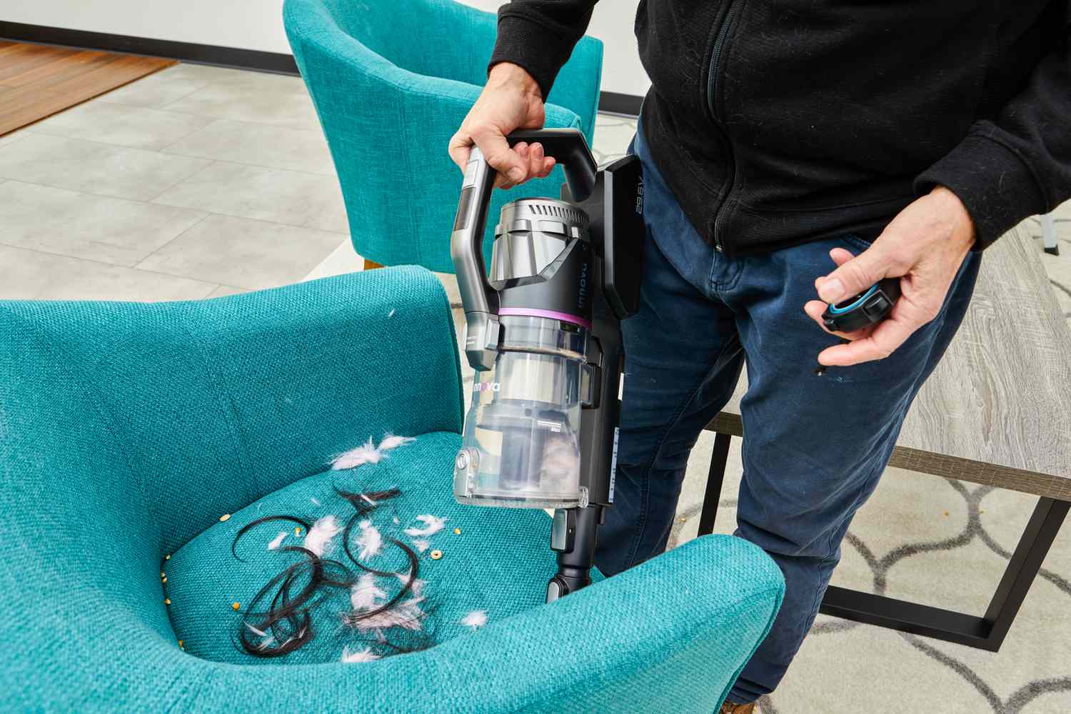 Person cleaning hair and other spills from sofa using the Innova Cordless Stick Multi-Surface Vacuum