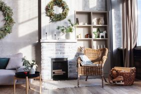 Tidy and calm home with whitewashed fireplace, woven rattan side chair, and evergreen wreaths