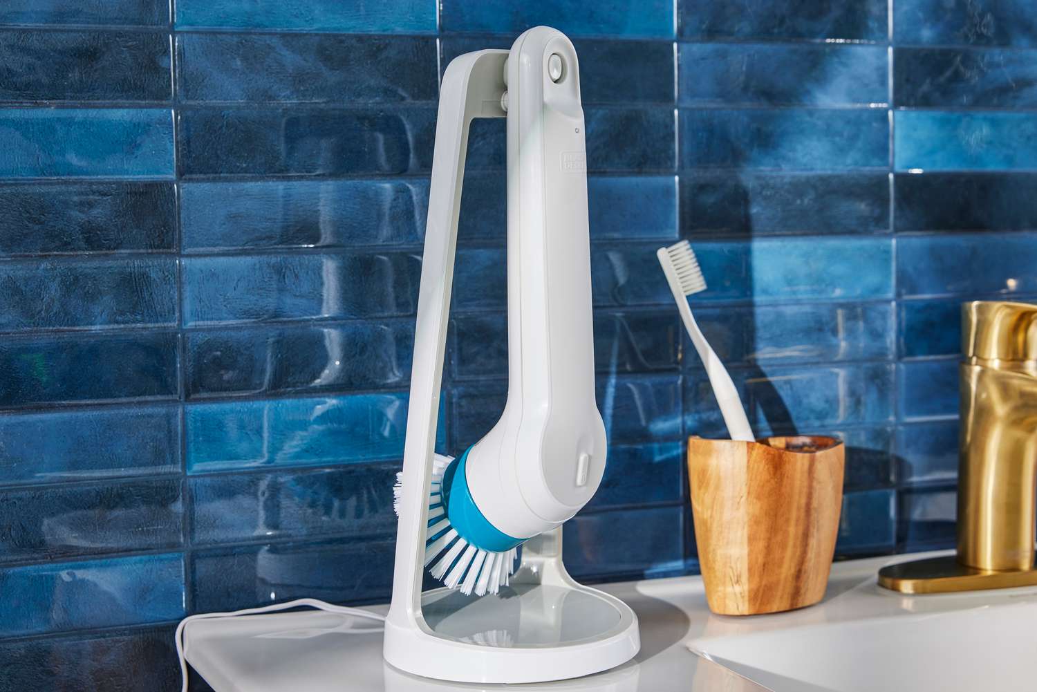 A Black+Decker Grimebuster Pro Power Scrubber Brush on its stand sits on a bathroom sink