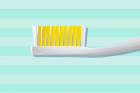 White toothbrush with yellow bristles against a blue striped background