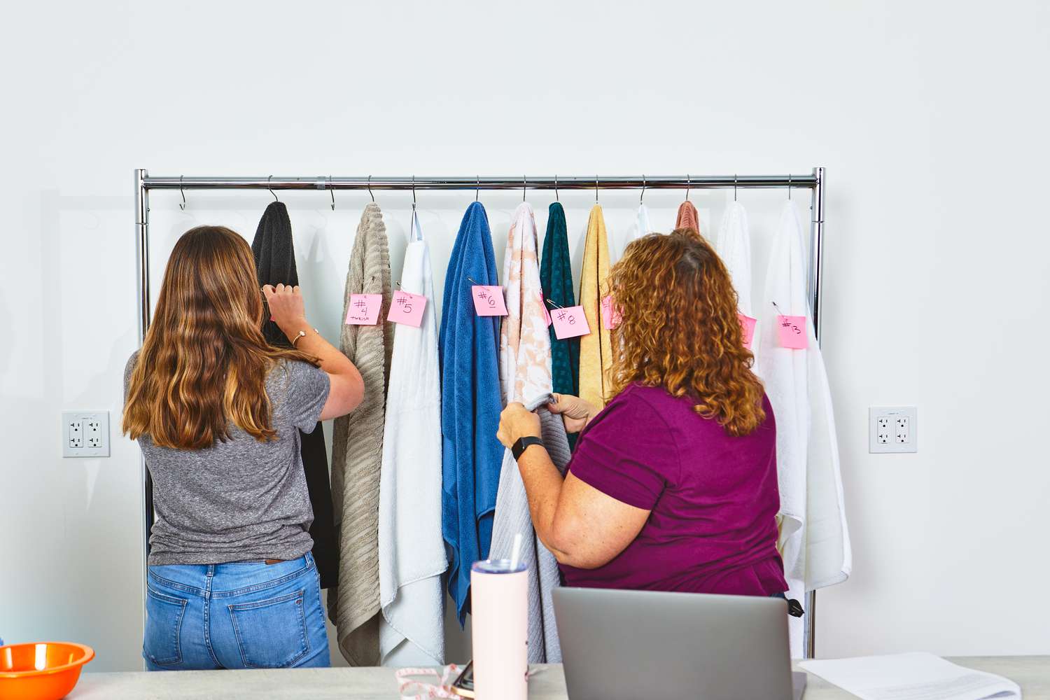 Women testing bath towels on rack