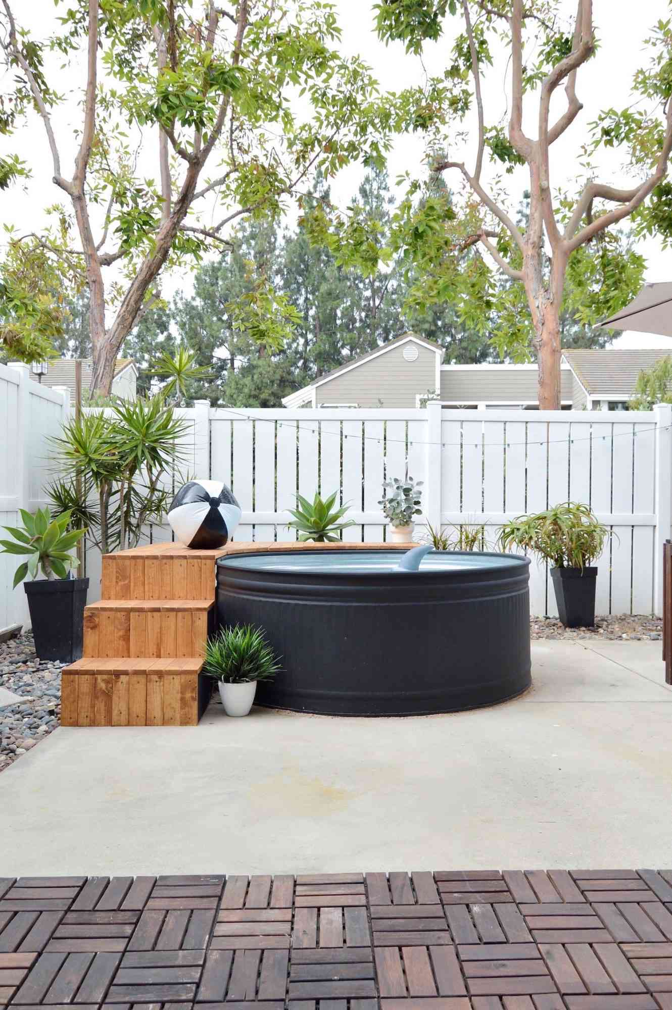 black stock tank pool next to white outdoor fence in backyard