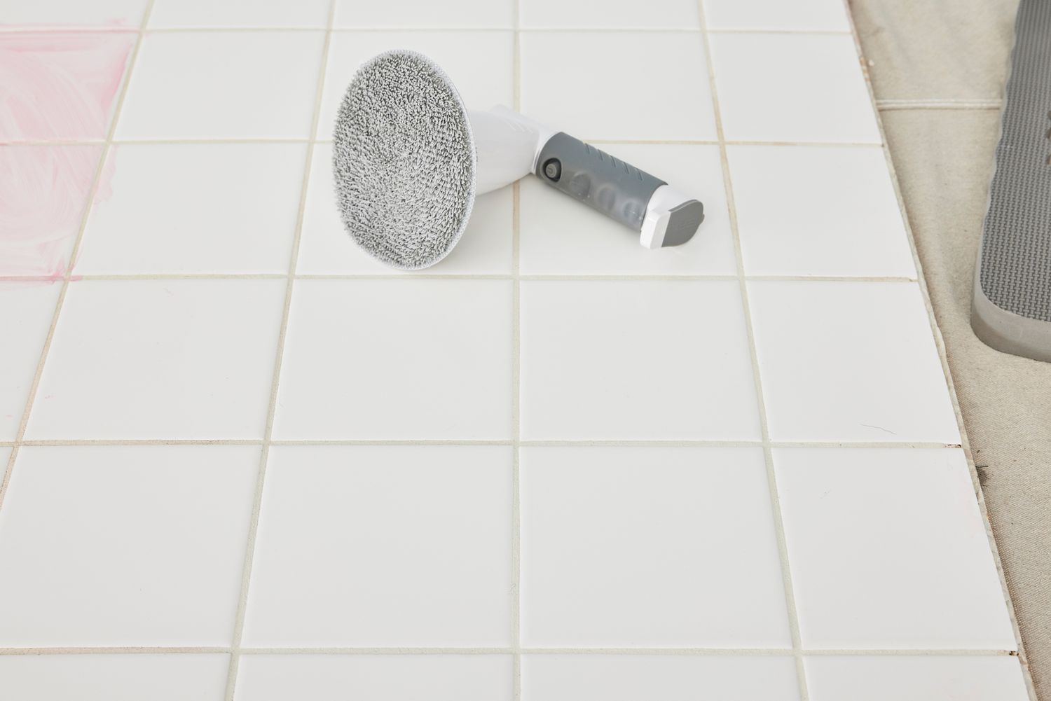 An IEZFIX Electric Spin Scrubber lying on white tile