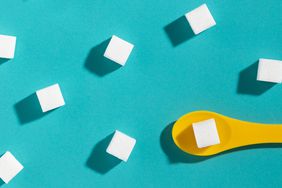 sugar cubes and yellow spoon against a blue background