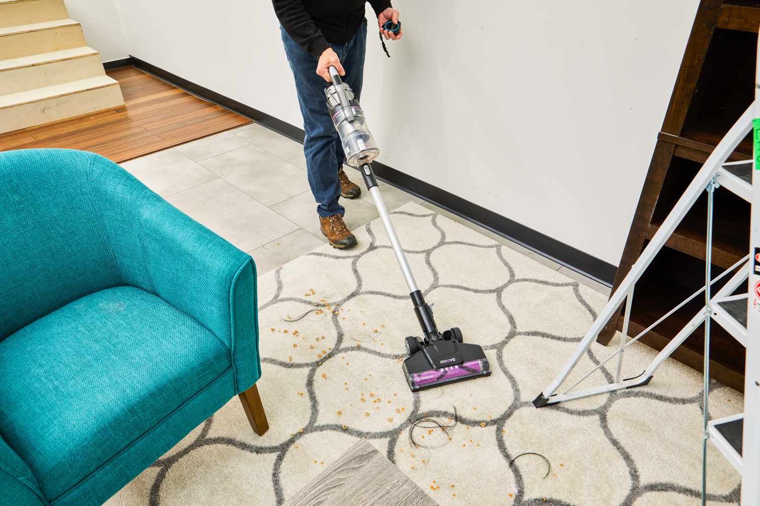 Person using the Innova Cordless Stick Multi-Surface Vacuum to clean food and hair from a carpet 