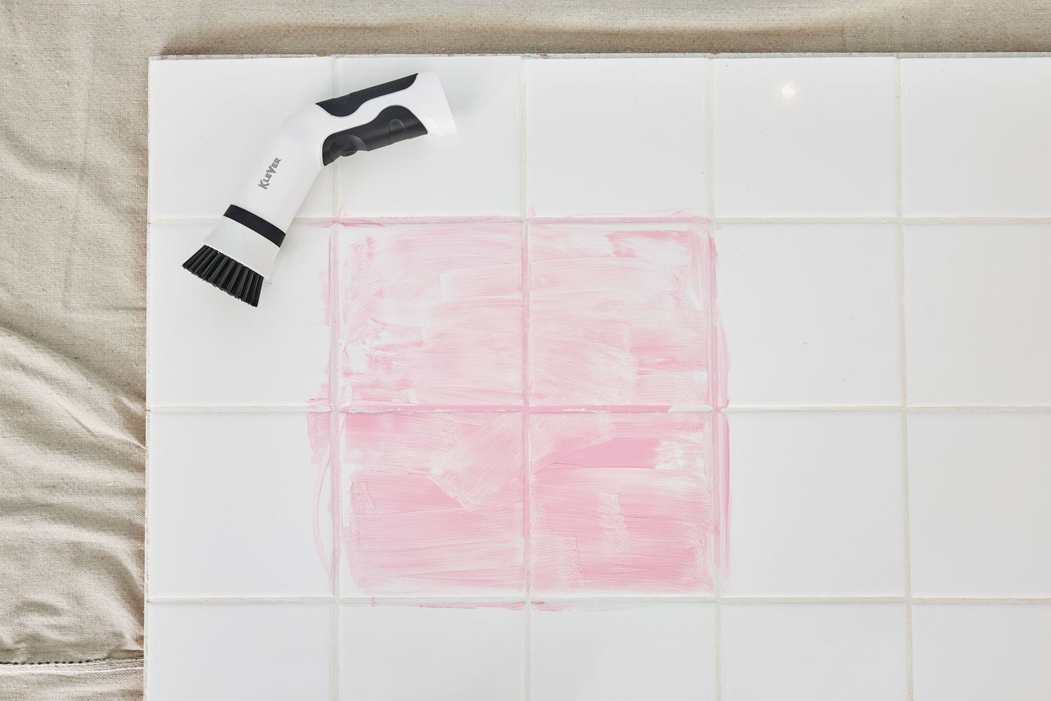 A Klever Electric Spin Scrubber with 8 Brushes lying on white tile stained with red marker