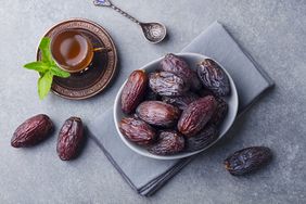 Fresh Medjool Dates in a bowl with tea. Ramadan kareem. Grey stone background. Top view.