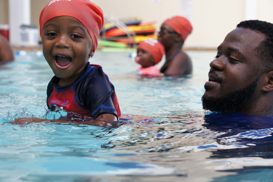 Child learning to swim with parent
