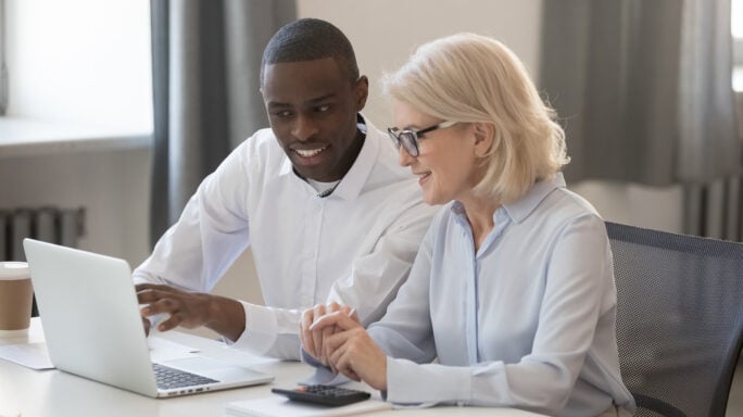 Diverse businessman and businesswoman accountants working together on pc discussing online software business strategies collaborating on computer, office colleagues team planning project use laptop