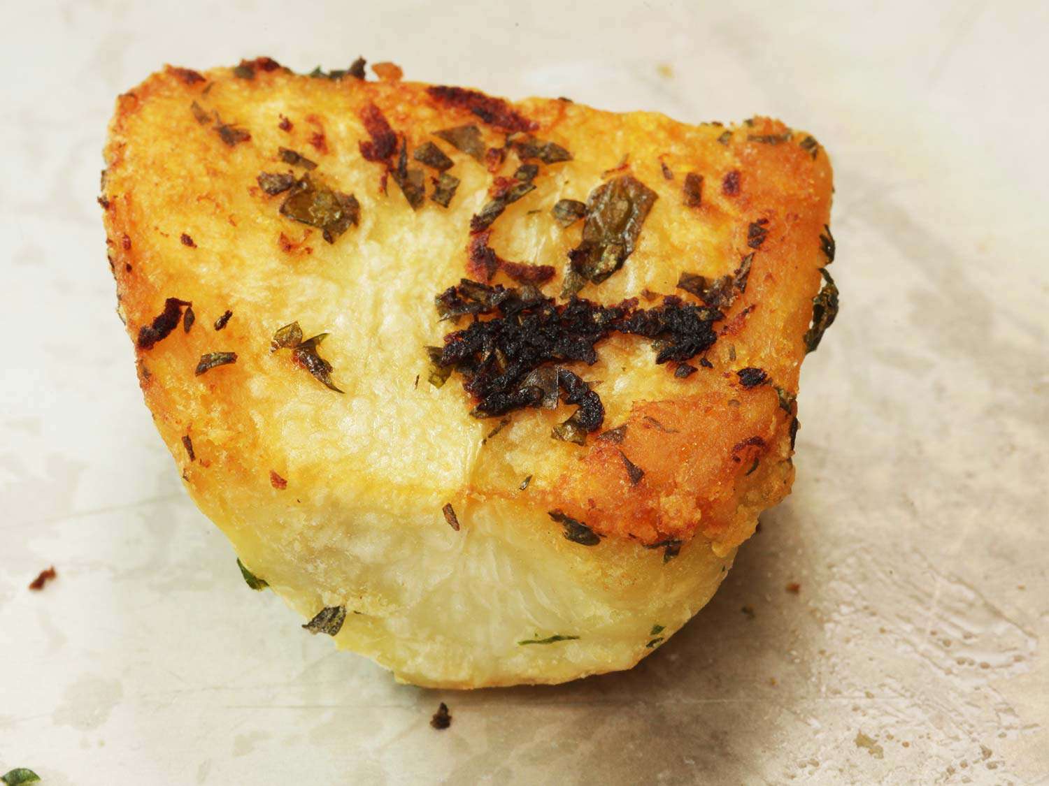 Roast potato with burned garlic and rosemary on its exterior.