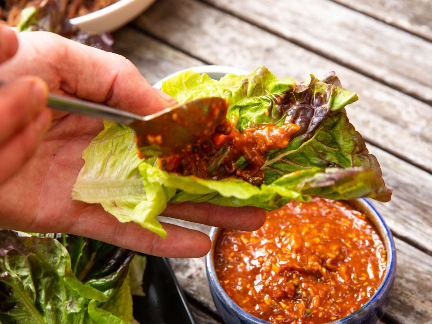 Spreading ssamjang on a piece of lettuce.