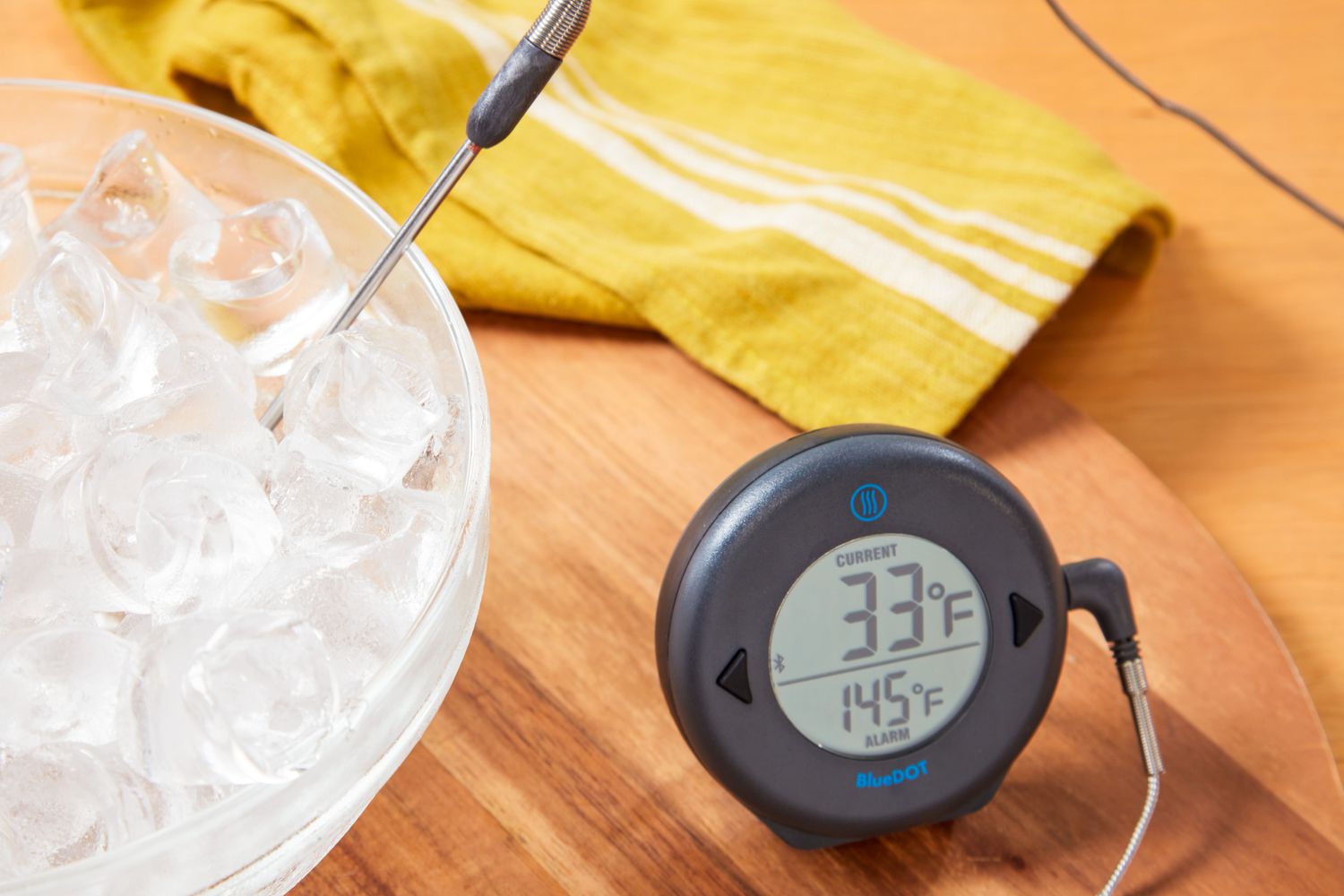 blue dot thermometer on a wooden surface with bowl of ice next to it